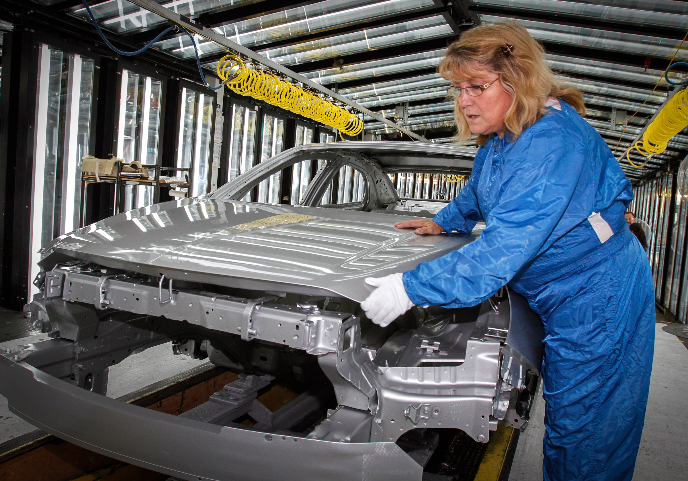 Worker inspecting a car body in an automotive factory
